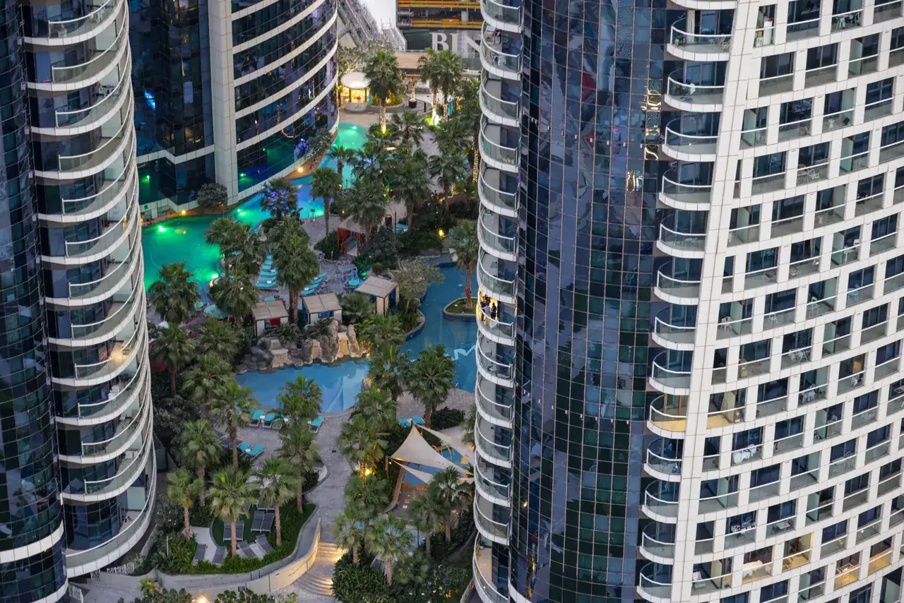 Letecký pohled na dubajské rezidenční věže s bazény, typická zástavba pro krátkodobé pronájmy