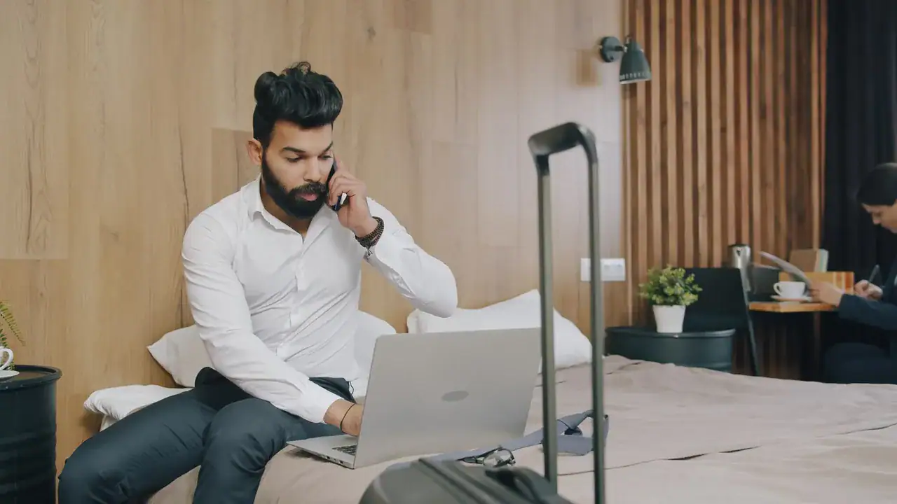 Host na delším pobytu pracuje s notebookem a telefonem v pronajatém apartmánu