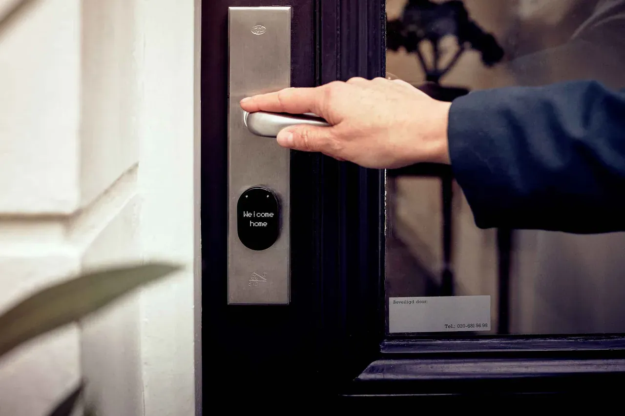 Hand opening an apartment front door with a smart lock and digital keypad, required equipment for a Dubai holiday home